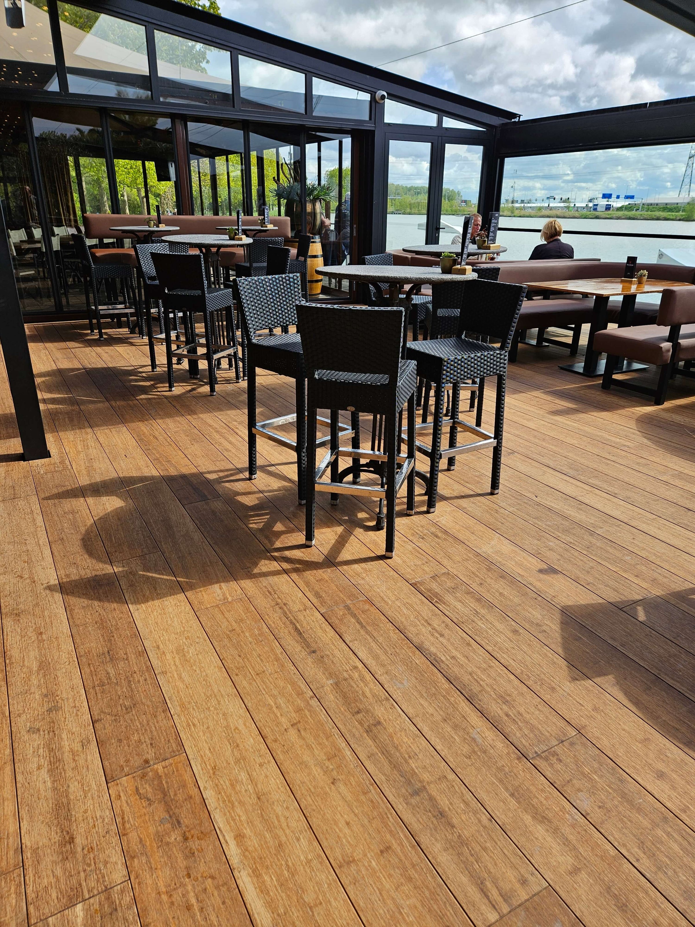 Außenterrasse eines Restaurants mit langlebigen Closed Decking Bambus-Terrassendielen Colon von aMbooo und stilvoller Sitzmöblierung.