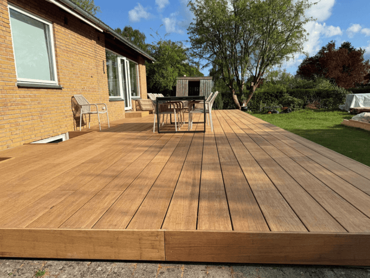 Hochwertige Bambusterrasse mit breiten Terrassendielen, großzügiger Sitzfläche und modernem Design in einem gepflegten Hausgarten. In der Farbe Sand als Komplettpaket mit einer Aluminium Unterkonstruktion.
