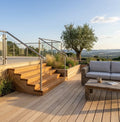 Großzügige Bambusterrasse mit integrierter Treppe und Edelstahl-Glasgeländer. Die helle Terrassenanlage schafft einen modernen und einladenden Außenbereich mit Blick in die Natur.