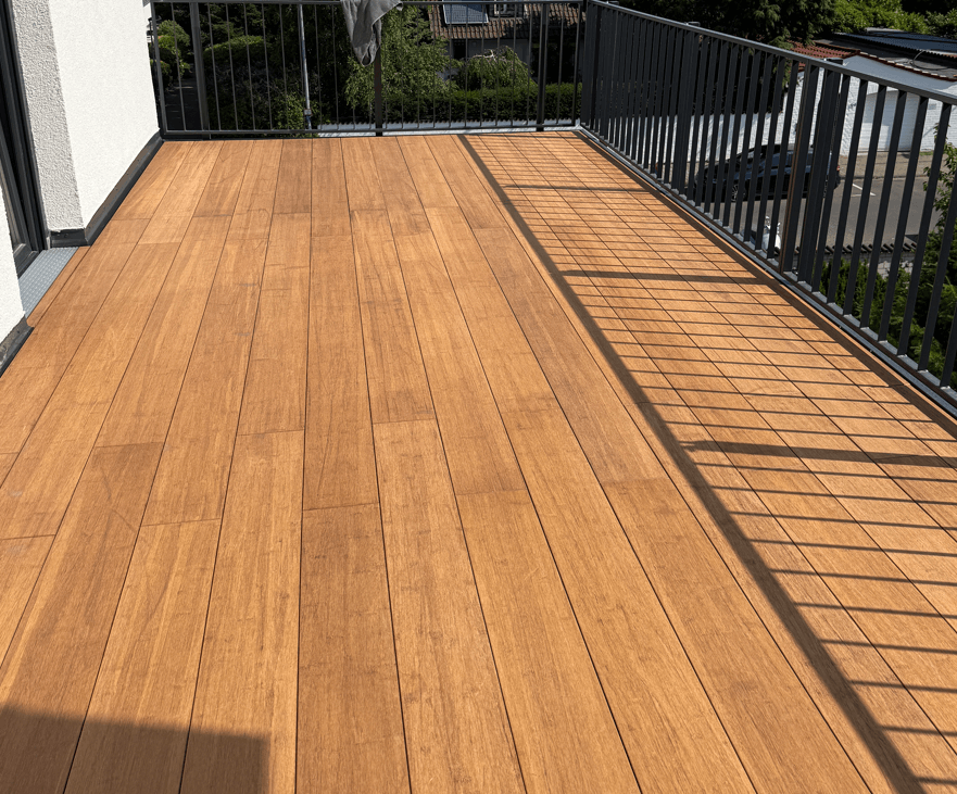 Große Dachterrasse mit hellbraunen Bambus-Terrassendielen in geschlossener Verlegung (Closed Decking -  Cristobal ), umgeben von einem schwarzen Metallgeländer.