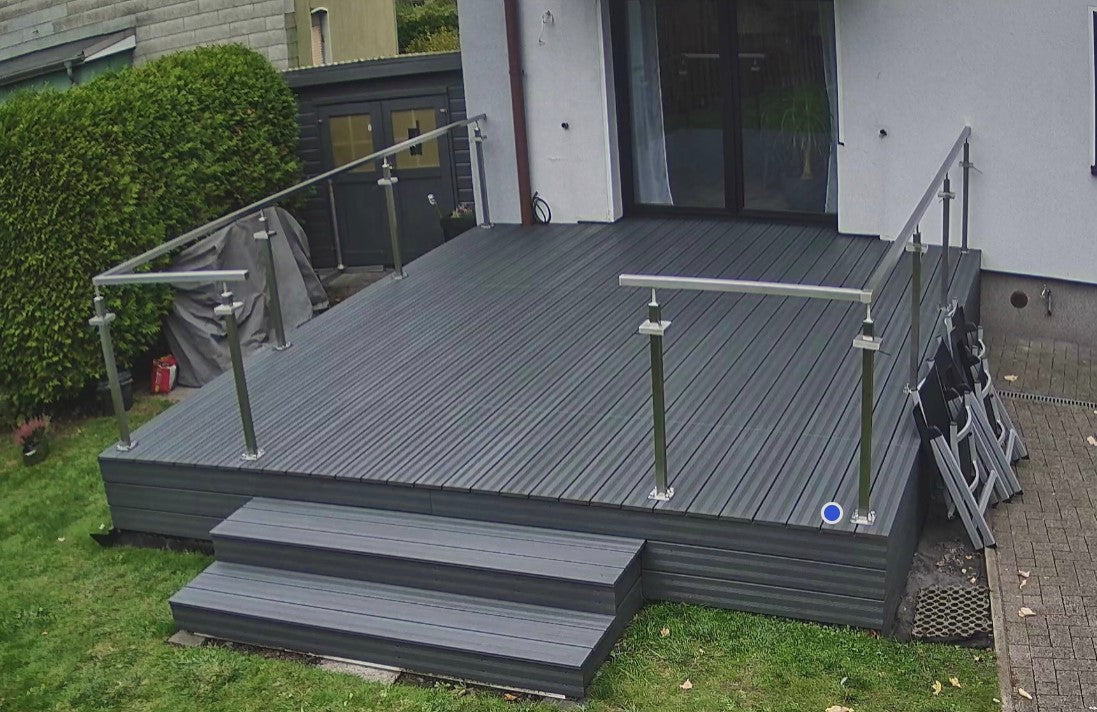 Moderne Terrasse in grau nach dem oelen, mit breiter Treppe, Edelstahlgeländer und Zugang zum Haus. Die Terrasse liegt ebenerdig und grenzt an einen gepflegten Garten.“