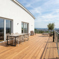 Großzügige Holzterrasse mit Esstisch, Liegen, Glasgeländer und weitem Blick über die Stadt.
