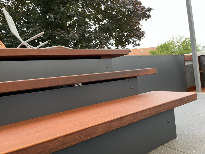 Nahaufnahme einer modernen Außentreppe mit braunen Bambus-Trittstufen und anthrazitfarbenen Setzstufen auf einer Terrasse.